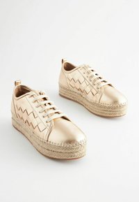 Fémes arany színű sportcipők szövetmintával, fűzős záródással és espadrille-stílusú zsákvászon platformtalppal. Sima textúra varrással.