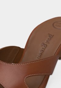 Καφέ δερμάτινο σανδάλι slip-on με ανοιχτά δάχτυλα και χαμηλό τακούνι, με εμφανή ραφή και ανάγλυφο λογότυπο "Paul Green" στην εσωτερική σόλα.