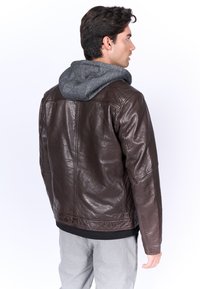 Bruine leren jas met een grijze hoodie-voering, met een slank ontwerp en een textuurafwerking. Zichtbare stikseldetails en een relaxte pasvorm.