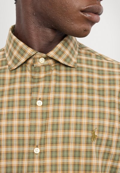 Plaid shirt in green and beige with a button-down collar, featuring a small embroidered logo, and plastic buttons on the front.