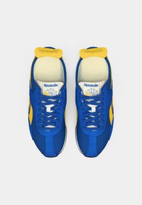 Kaks sinist ja kollast Reebok'i spordijalatsit vaadatuna ülalt, seotud paeltega ning brändi sildid nähtavad.