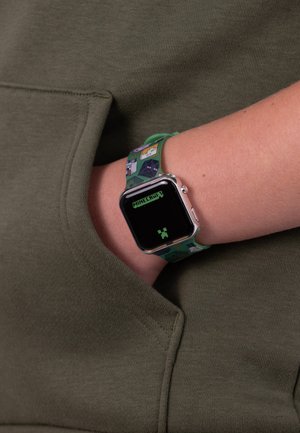 Orologio a tema Minecraft verde con quadrante rettangolare, display digitale e cinturino in silicone testurizzato che presenta personaggi e elementi del gioco.