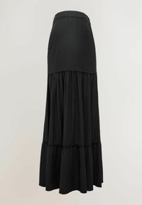Jupe longue noire à volants avec taille élastique et panneaux de tissu froncés sur un fond neutre.