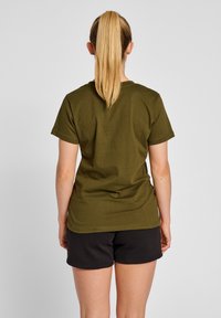 Olivengrøn bomulds T-shirt med korte ærmer, afslappet pasform og rund halsudskæring, parret med sorte shorts. Enkel design uden mønstre.
