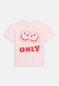 Ανοιχτό ροζ μπλουζάκι με δύο κόκκινα χαμογελαστά πρόσωπα και το κείμενο «REBEL LOVE ONLY» τυπωμένο στην πλάτη με ξεθωριασμένα μπεζ και έντονα κόκκινα γράμματα.