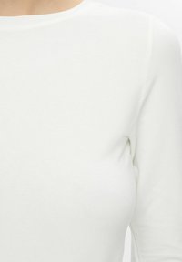 Witte, nauwsluitende blouse met lange mouwen van gladde stof en een ronde halslijn, met een subtiele ribbelstructuur.