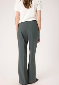 Sive, široke hlače iz gladkega materiala. Imajo preprost dizajn z udobnim krojem, minimalnimi šivi in brez vidnih kovinskih delov.