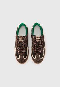 Sneakers marroni e crema con accenti verdi. Parte superiore testurizzata con lacci, colletto imbottito e suola in gomma. Presenta sezioni perforate sui lati.