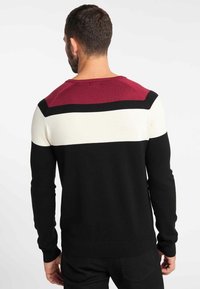 Sweter dzianinowy z poziomymi paskami w odcieniach burgundu, kremowym i czarnym. Długie rękawy oraz ściągacze przy mankietach i dolnej krawędzi. Luźny krój.