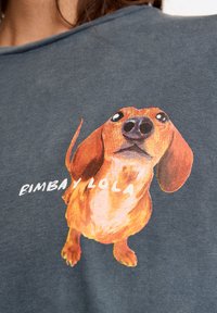Węglowoszara koszulka z kolorową, ilustrowaną grafiką jamnika i napisem "BIMBA Y LOLA" pod obrazkiem.