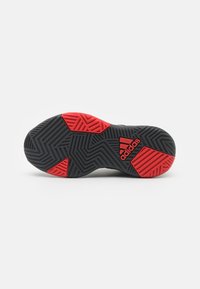Semelle de chaussure en caoutchouc noire et rouge avec un motif en zigzag texturé et un logo Adidas bien visible. Conçue pour l'adhérence et la durabilité.