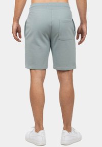 Lichtgrijze katoenen shorts met een elastische tailleband, zijzakken en een achterzak. Gekozen in combinatie met witte sneakers. Geen zichtbare patronen.