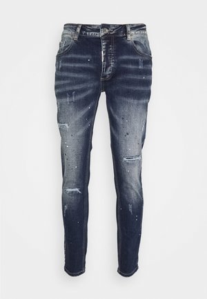 Dunkelblaue, schmal geschnittene Jeans mit Used-Details, verblassten Stellen und kleinen weißen Farbspritzern, mit Vordertaschen und Knopfverschluss.