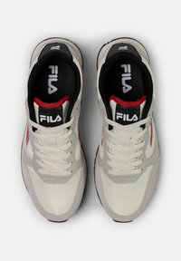 Vitaid sneakers i vitt med en texturerad yta, som har grå och röda detaljer, svart foder och en framträdande logotyp på tungan.