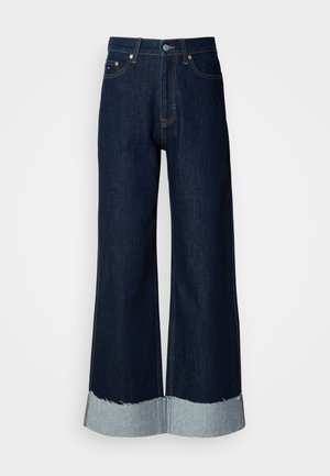 Vide ben mørke denim jeans med en frynset, lys denim kant. Har klassisk fem-lomme stil og metalhardware i taljen.