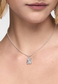 Srebrny naszyjnik z koralikami z kwiatowym wisiorkiem, który posiada szczegółowe wzory płatków. Łańcuszek jest krótki i dopełnia wisiorek.