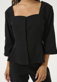 Čierny peplum top so štvorcovým výstrihom, tromi štvrtinovými rukávmi a predným gombíkovým zapínaním. Hladký materiál s priliehavým strihom.