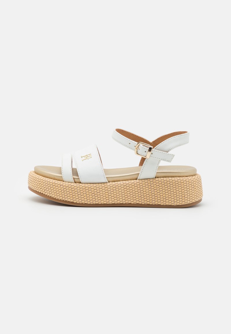 White sandal with two wide straps, adjustable ankle strap, and a woven-style platform sole in tan with a subtle embossed logo accent.