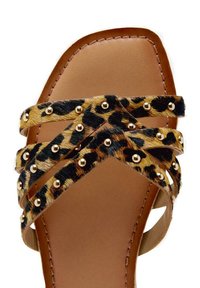 Infradito con stampa leopardata, dotate di fasce incrociate in pelliccia sintetica, rifinite con borchie dorate e con un sottopiede beige. Design con suola piatta.