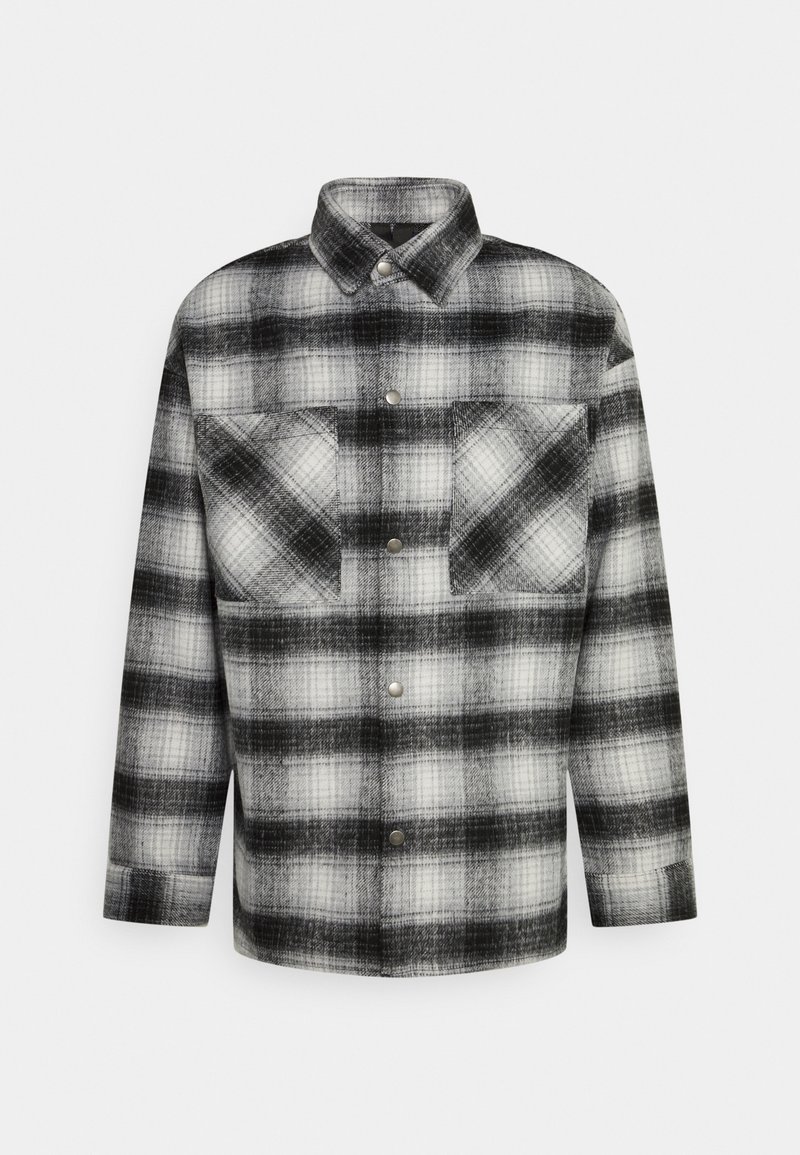 Sorte og hvide ternet skjortejakke lavet af flannel, har en knapfront, krave og to brystlommer.