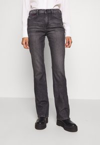 Dark gray straight-leg jeans made from denim. Features front pockets, subtle stitching, and a slight distressed look. Styled with black platform shoes.