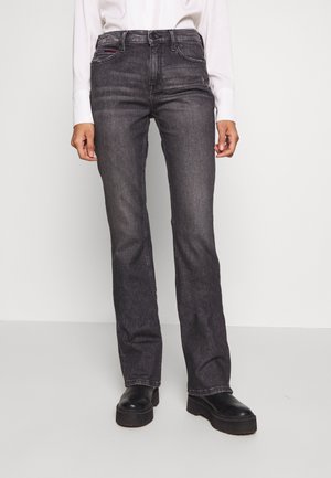 Dark gray straight-leg jeans made from denim. Features front pockets, subtle stitching, and a slight distressed look. Styled with black platform shoes.