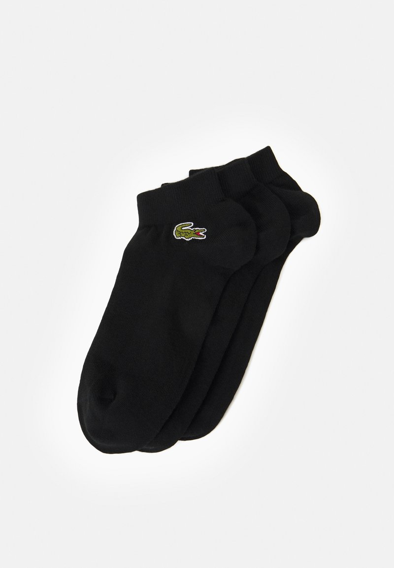 Chaussettes en coton noir à coupe basse, arborant un petit logo de crocodile vert sur le côté. Texture douce avec un ajustement confortable.