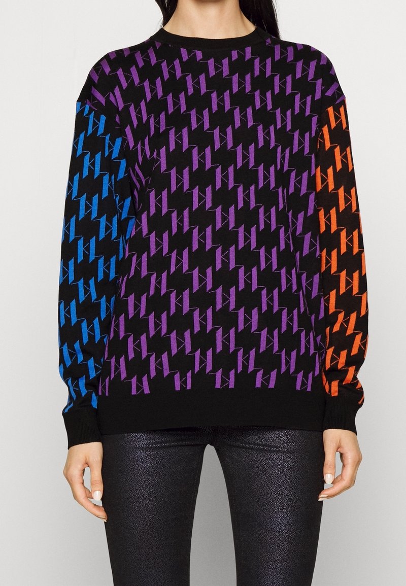 Felpa colorata con una base nera e un motivo geometrico in viola, blu e arancione. Maniche lunghe e polsini a coste.