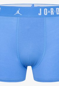 Blaue Baumwoll-Boxershorts mit enger Passform. Sie haben einen einfarbig blauen Körper und einen elastischen Bund mit weißem "JORDAN"-Schriftzug und Logo.