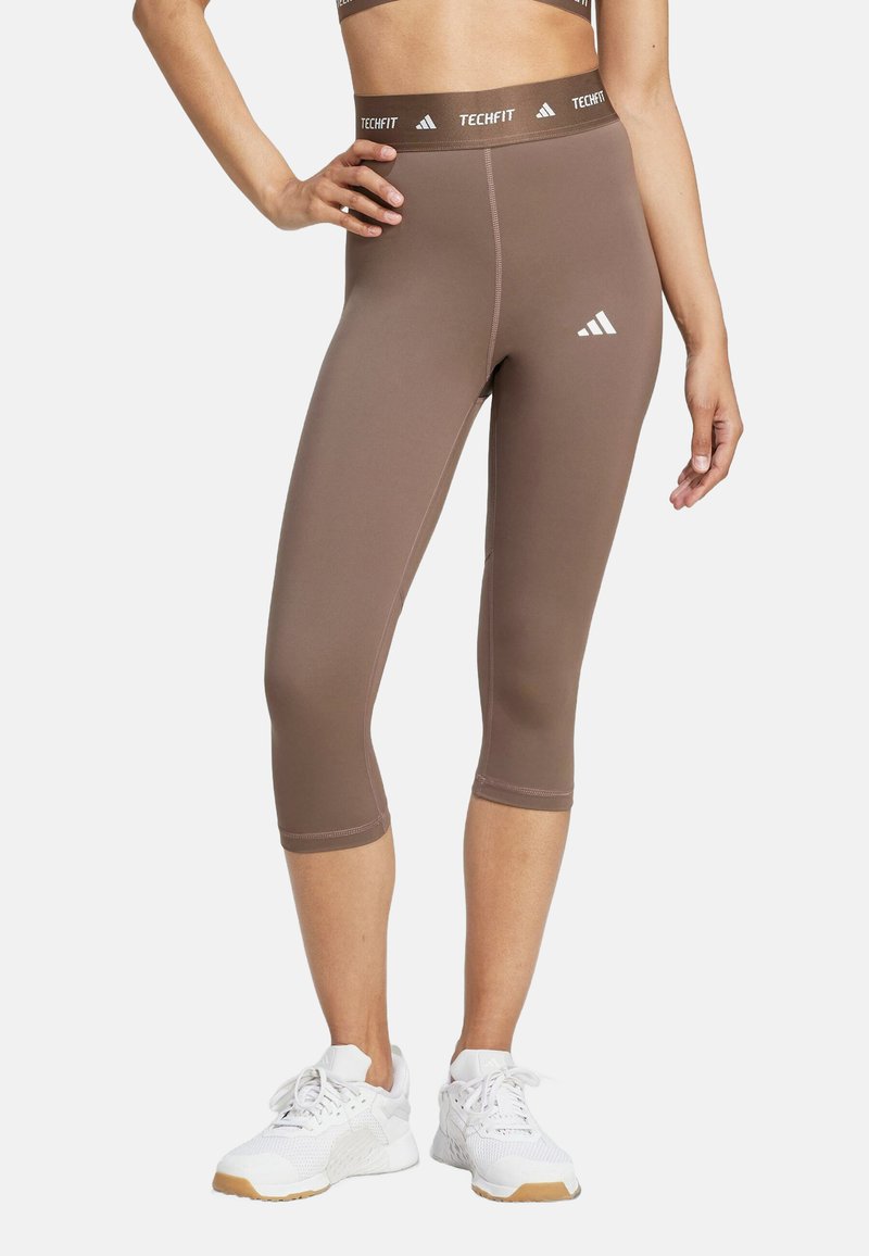 Braune Capri-Leggings aus elastischem Material, mit einem einfarbigen Design, figurbetonter Form und kontrastierendem schwarzen Taillenbund mit Logo.