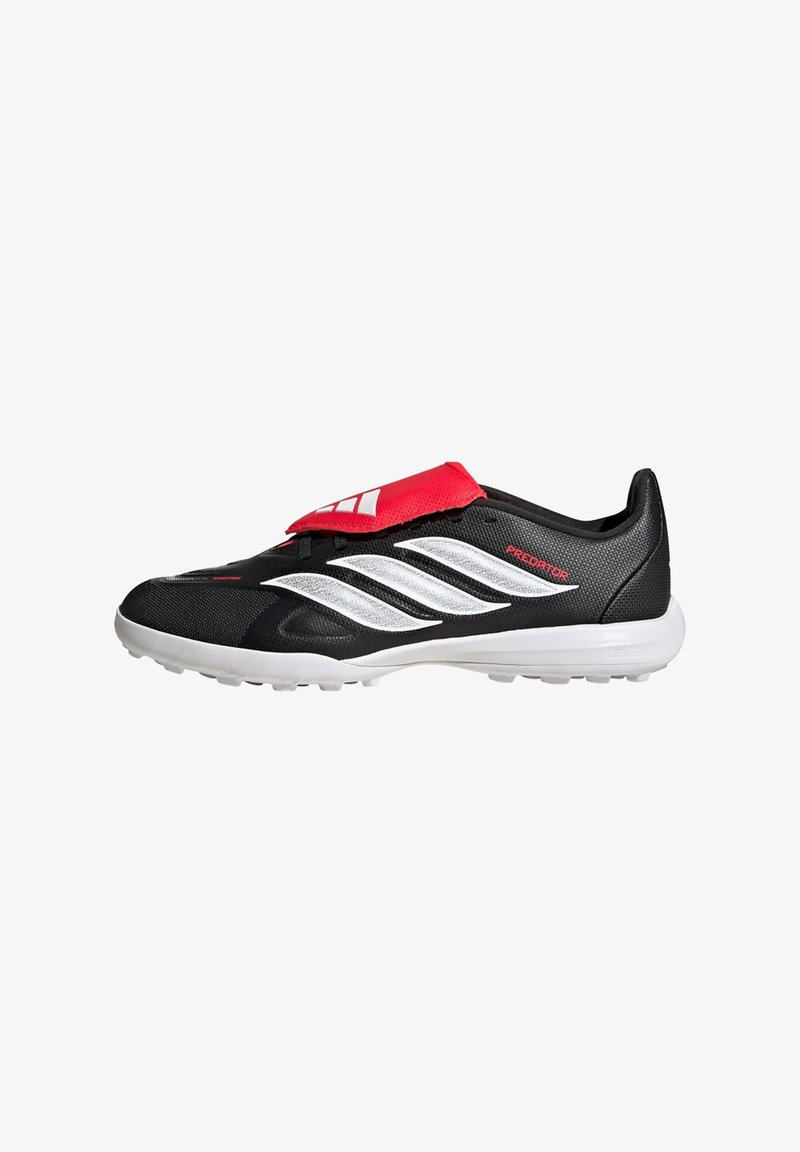 Chaussure de football Adidas Predator noir et blanc avec un rabat de languette rouge et une semelle blanche ornée de petits crampons.