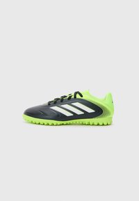 Voetbalschoenen met een zwarte bovenkant, neon groene accenten, drie witte strepen, een gestructureerd oppervlak en een rubberen zool met kleine noppen.