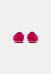 Bailarinas de ante fucsia con punta redonda, suela plana color tostado y pequeño lazo en la parte posterior. Textura suave, sin patrones visibles ni herrajes.
