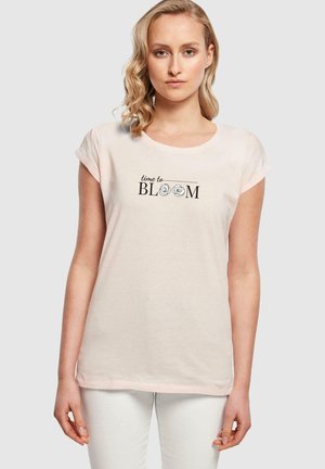 Lyse rosa bomulls t-skjorte med korte ermer, rund hals, og svart tekst "time to BLOOM" dekorert med utsmykkede rosemotiver.