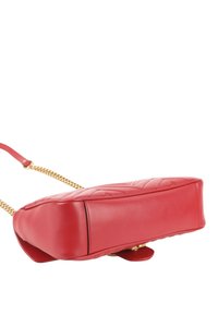 Sac à main en cuir rouge avec motif matelassé et bandoulière chaîne dorée, présenté reposant sur son côté sur fond blanc.