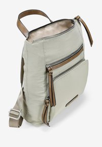 Bolso de hombro de nailon beige con acentos de cuero marrón, que cuenta con dos bolsillos con cremallera y una correa ajustable. Textura suave, diseño moderno.