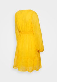 Vestido amarelo de mangas compridas com um tecido texturizado, cintura ajustada e saia em camadas. Apresenta um decote redondo e uma silhueta fluida.