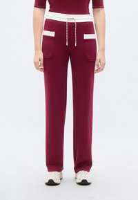Μπορντό παντελόνι με άνετη εφαρμογή, λευκή κορδόνι στη μέση και δύο μπροστινές τσέπες. Λεπτό ύφασμα με μαλακή υφή.