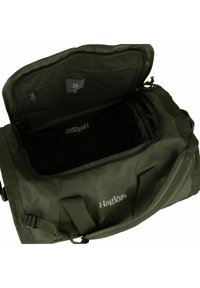 Borsa da viaggio verde scuro in materiale resistente; presenta un'ampia apertura, tasche con zip e un logo sul lato per un facile accesso e riporre gli oggetti.