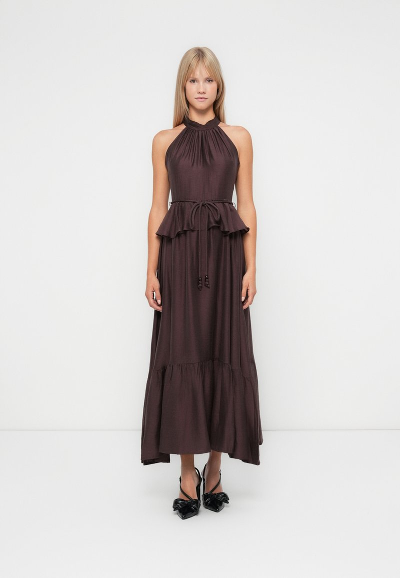 Lila Halftermaxikleid mit gerafftem Oberteil, Peplum-Taille und schichtigem Rock. Kombiniert mit schwarzen, schuhen mit Schleifenakzent.