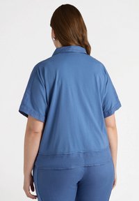 Camicia blu a maniche corte con colletto in un tessuto leggero, caratterizzata da un orlo dritto e una texture liscia. Adatta per un abbigliamento informale.