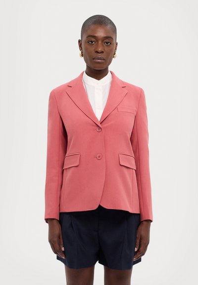 Pink tailored blazer with notched lapels, two front pockets, and a single button closure. Worn over a white collared shirt and navy shorts.