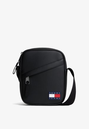 Kompaktowa czarna torba na ramię z ukośnym zamkiem i regulowanym paskiem, z logo Tommy Jeans w kolorach czerwonym, białym i niebieskim.