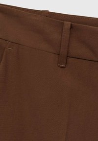 Pantalon en tissu tissé marron avec un devant plat, coupe droite et détails de couture subtils. Il présente une taille standard et une coupe classique.