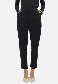 Pantalones negros de tiro alto con bolsillos laterales, que presentan botones de metal dorado y un diseño tapered. Textura de tela suave y longitud hasta el tobillo.