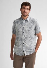 Camicia a maniche corte con bottoni di colore grigio chiaro, decorata con un motivo di foglie di palma scure, presenta una tasca sul petto e bottoni neri per la chiusura.