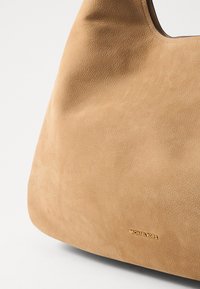 Smeškan kožni torba za rame u boji tamne kože, glatke teksture, zaobljenog oblika i suptilne zrnate površine. Ima zlatni akcent s logotipom "Michael Kors".