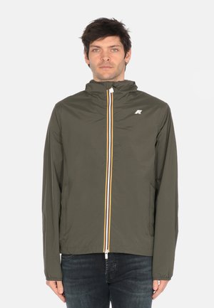 Giubbotto leggero verde oliva con colletto alto, zip frontale decorata con una striscia gialla e bianca, caratterizzato da un logo sul petto.