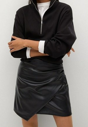 Sort sweatshirts med lynlås og lange ærmer, kombineret med et sort nederdel i kunstlæder med glat tekstur og detaljer med diagonale folder.