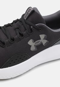 Black athletic shoe featuring a textured mesh upper, grey accents, and a white sole. Includes black laces and a logo on the side.
